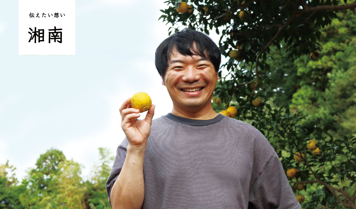 橙を手に笑顔のでこぼこファームの竹原さん